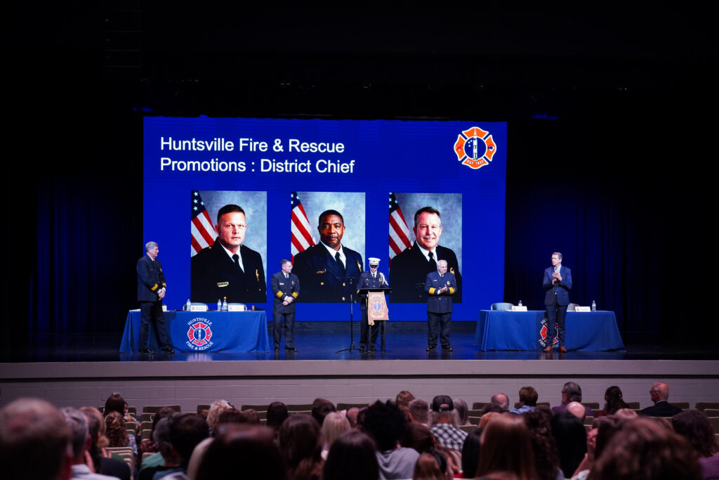 stage at awards ceremony with photos on projection screen