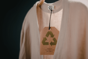 A pink sweater with recycled clothing tag hangs on a hanger