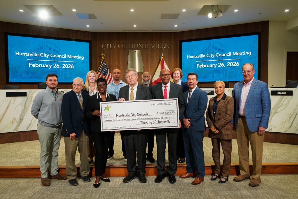 group of people pose for photo with oversized check