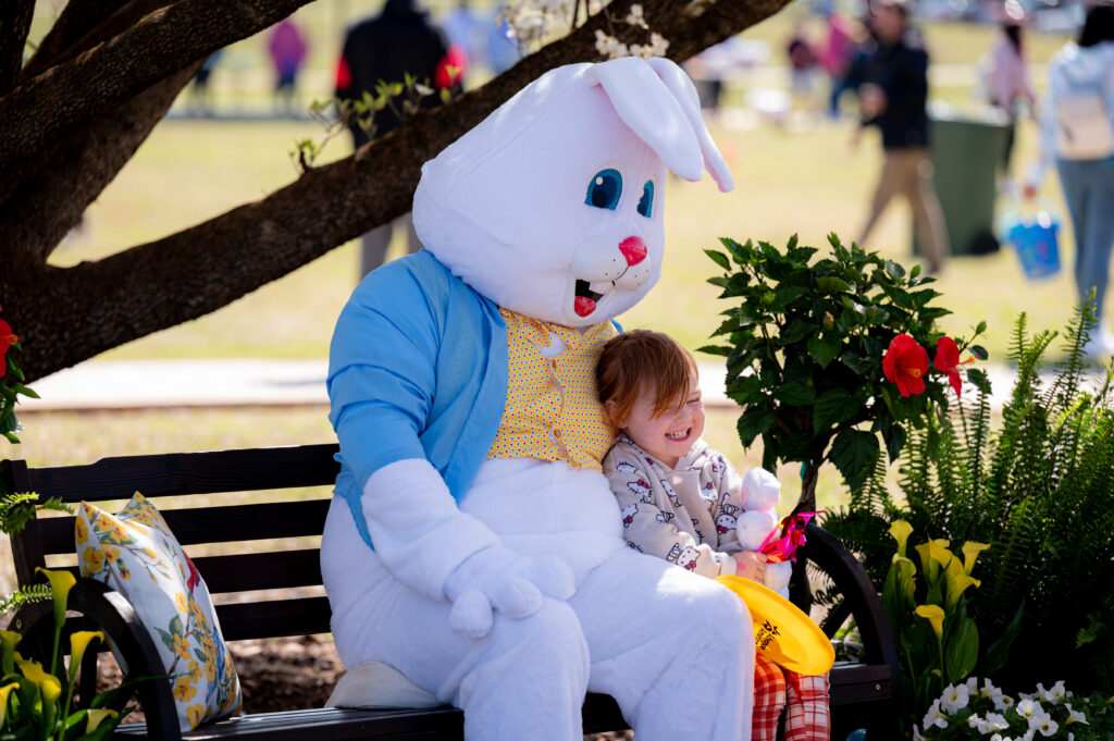 A child sits next to the Easter Bunny and smiles brightly
