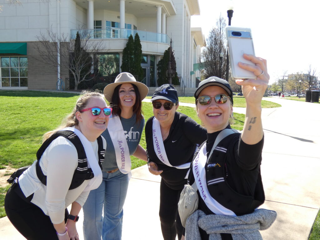 four women taking a selfie in a sunny park
