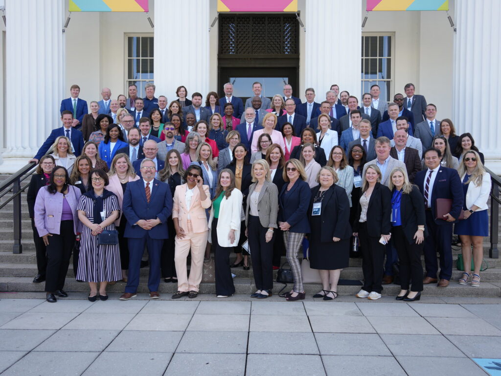 large group of people pose for photo outside building