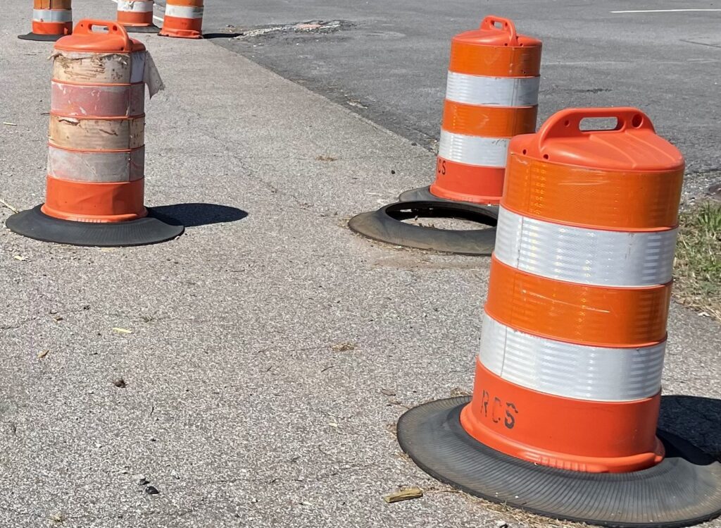 orange and white traffic barrels on a street