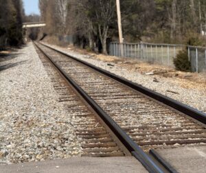 railroad tracks with gravel around it and trees in the background
