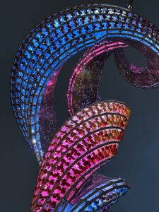 purple, red, orange, pink and blue lights in a swirling sculpture against a dark night sky