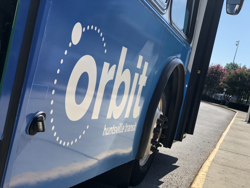 The word Orbit painted in white on the side of a blue painted bus