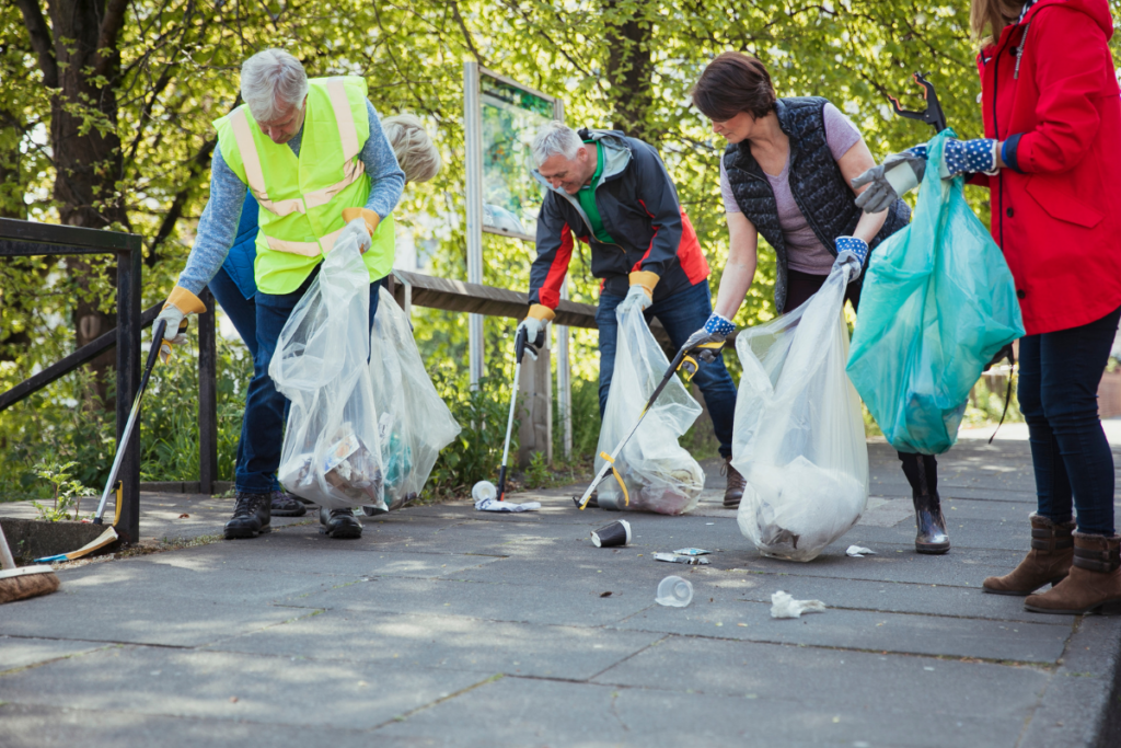 Four people on a bridge and walking path or greenway picking up trash
