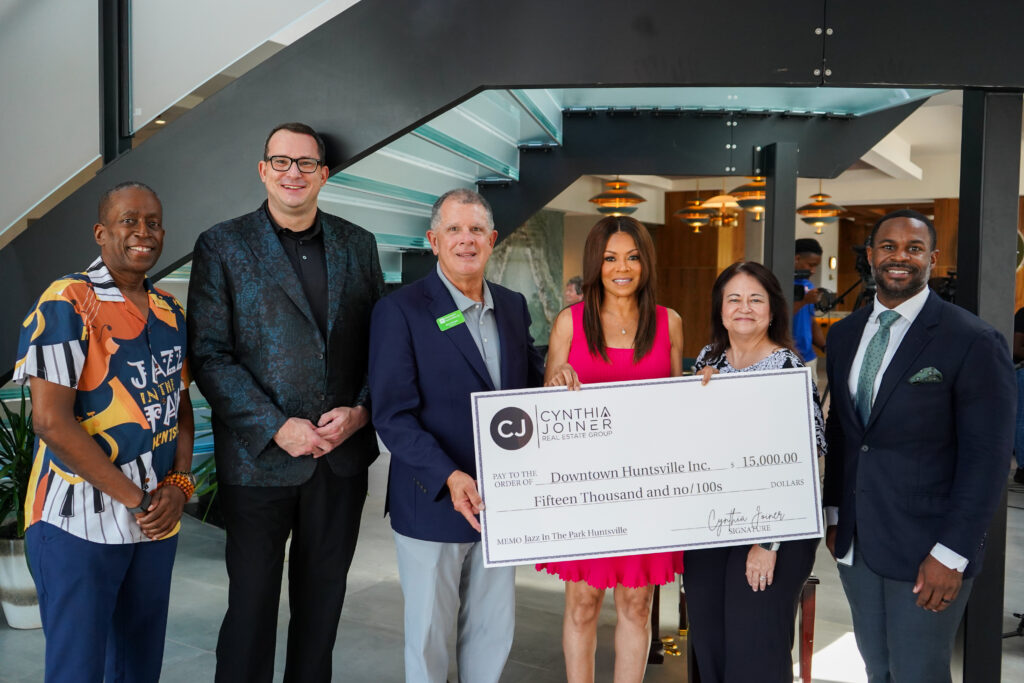 A group of well-dressed people pose for photo holding oversized check