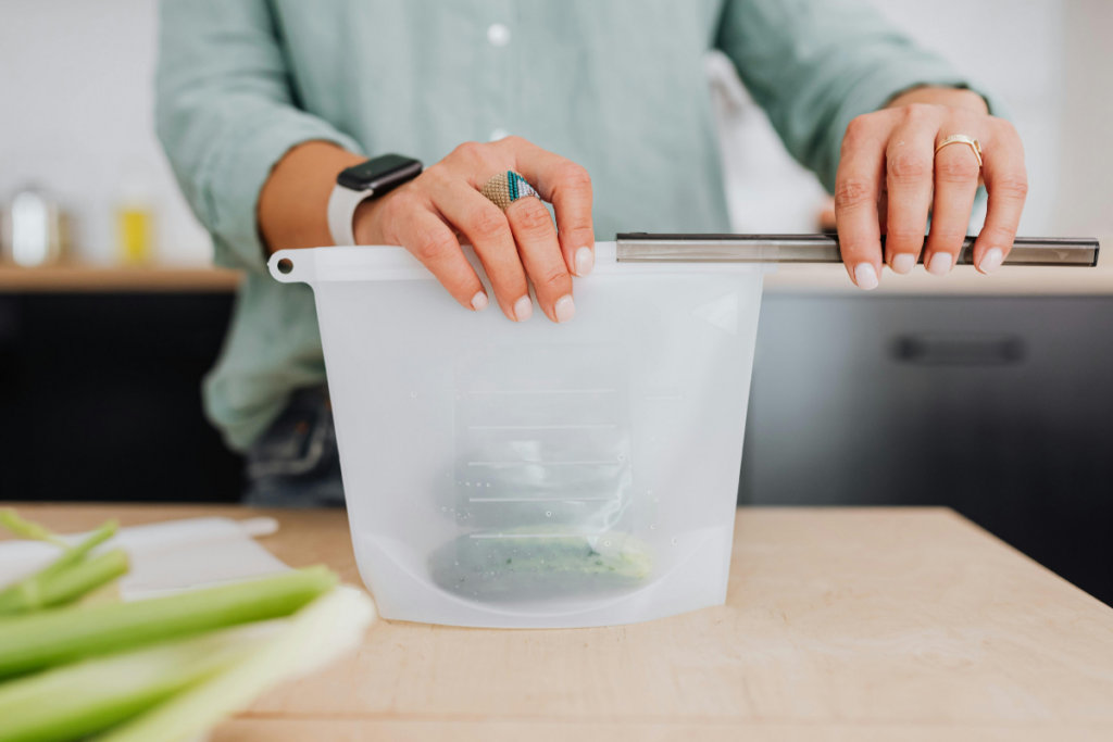 Zero Waste Week promotion graphic with a woman sealing up a silicone bag and meal-prepped food