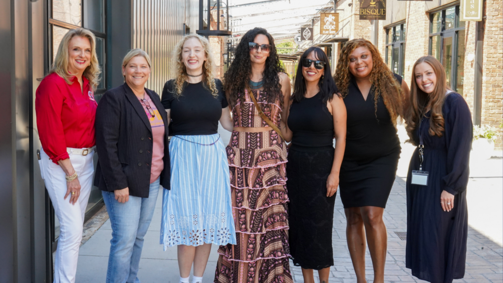 A group of seven women standing together for a photo, smiling. 