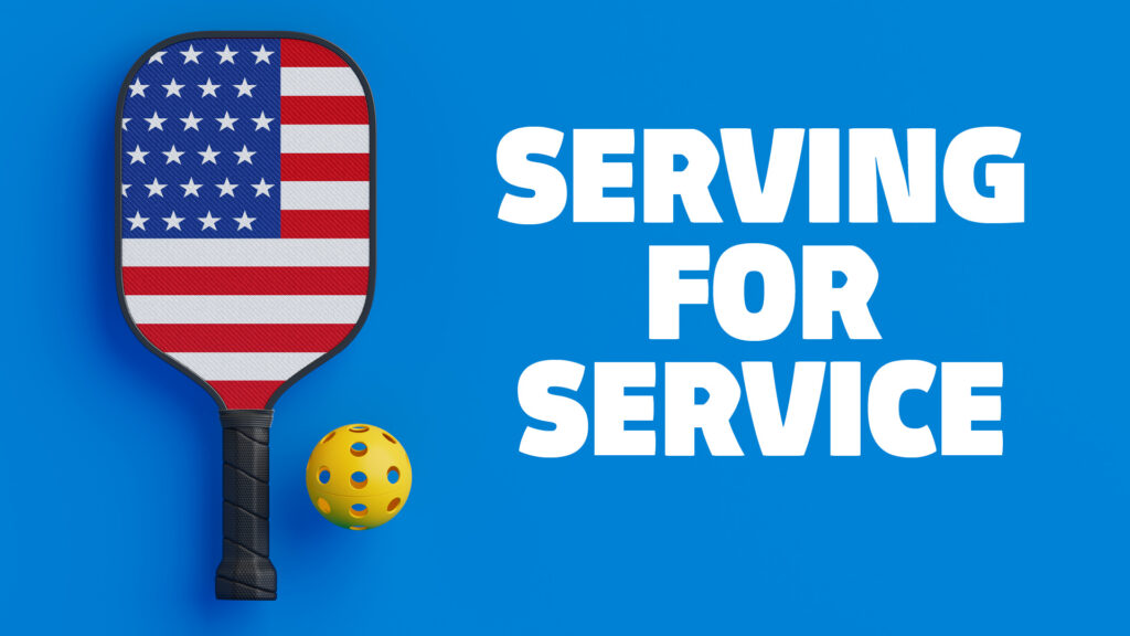 A pickleball paddle featuring the design of the United States flag is shown next to a yellow perforated pickleball on a bright blue background. Large white text on the right side reads “SERVING FOR SERVICE.”